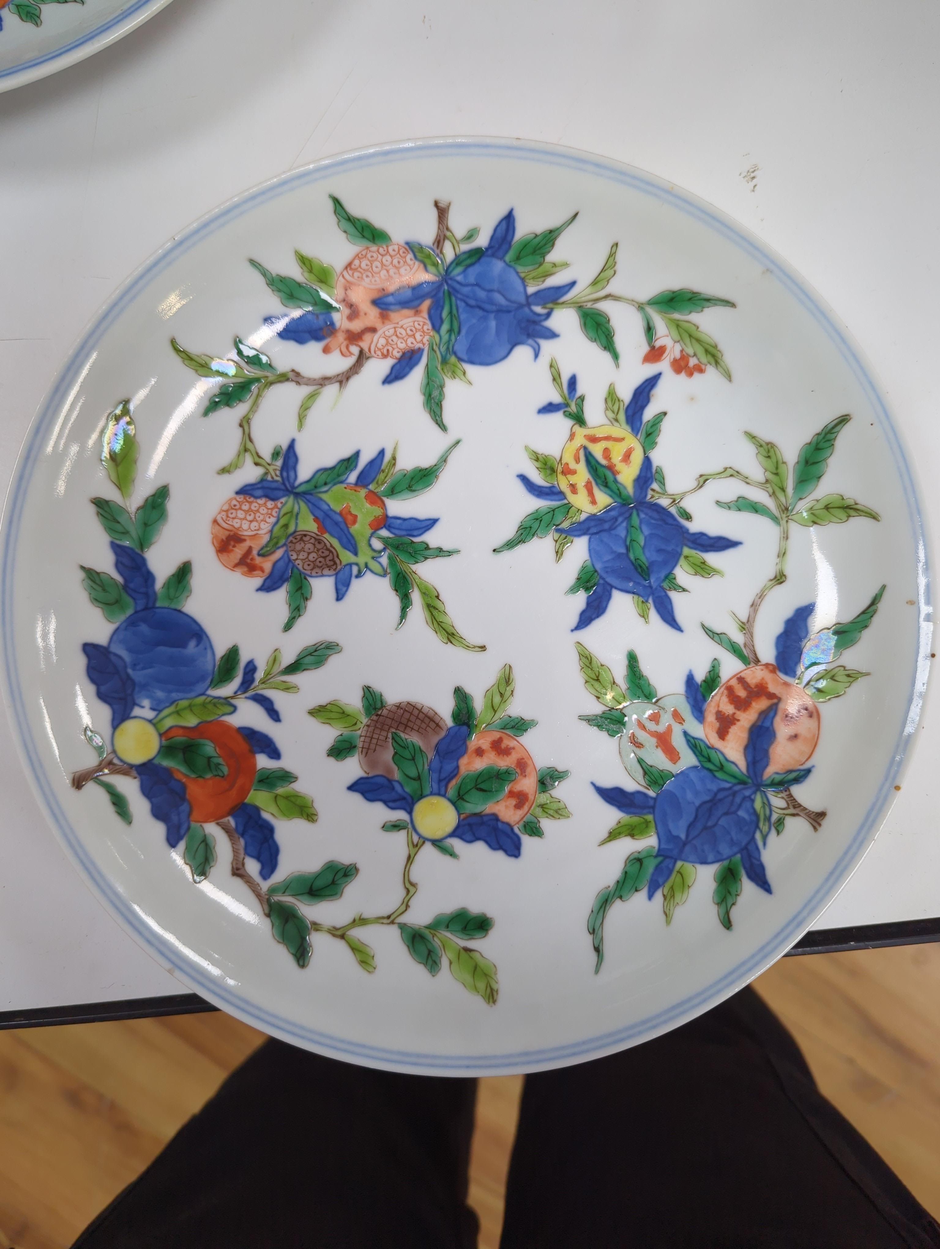 An 18th century Chinese famille rose bowl and a group of five Chinese wucai plates, each decorated with fruit, the bowl 23cm in diameter